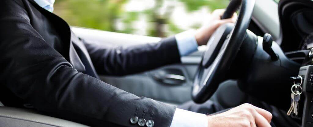 man with hands on steering wheel