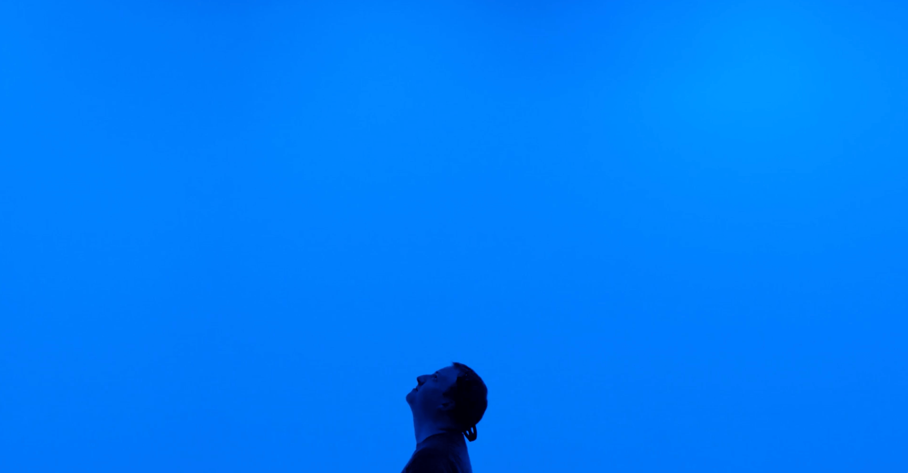 man looking up at blue background