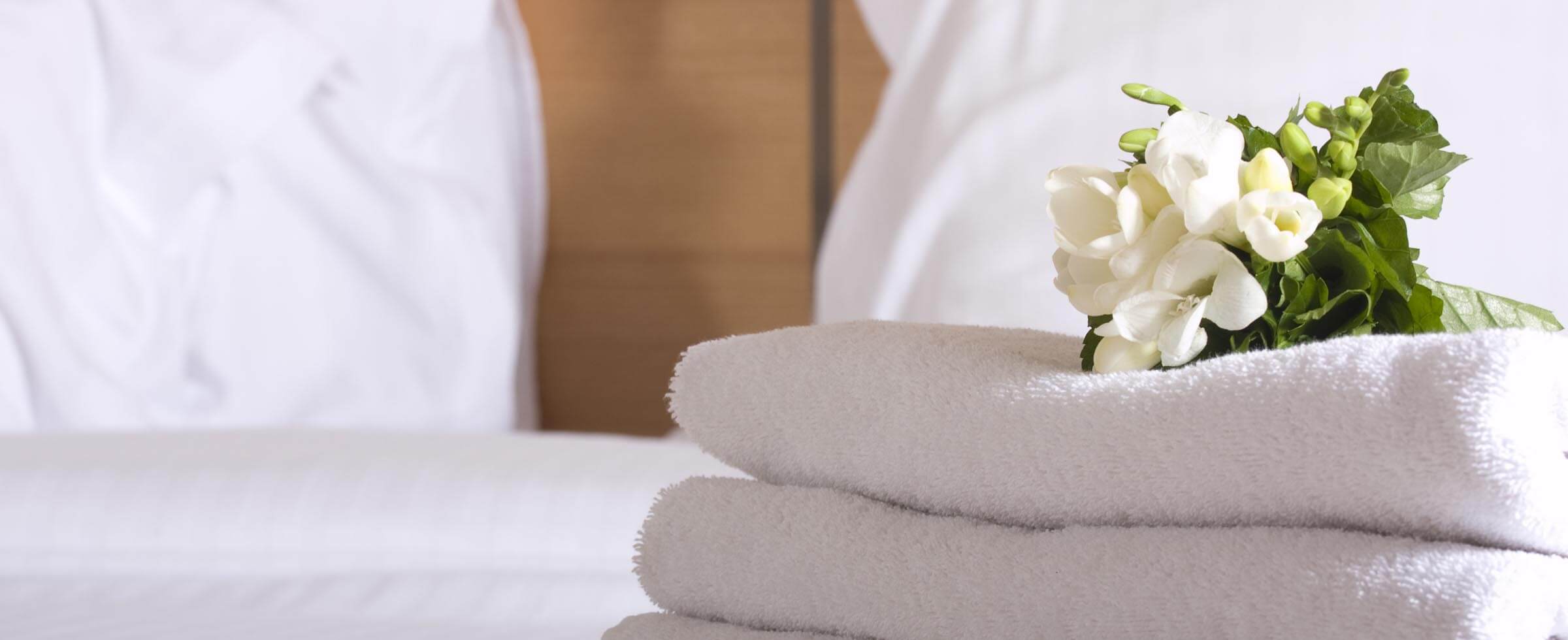 Handtücher und Blumen auf dem Bett im Hotel